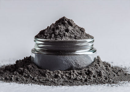 Iron in a powder glass jar filled with dark powder on a light gray background