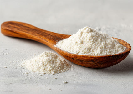 Wooden spoon filled with  Taurine white powder on a light gray surface